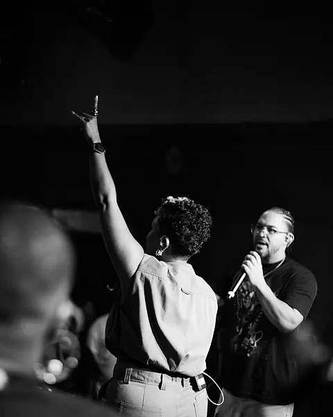 Cantora da Black SP de braço erguido pra plateia, com Daniel cantando ao lado