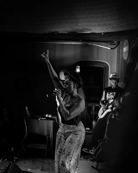 Cantora da Black SP no palco com o braço pro alto, o guitarrista atrás
