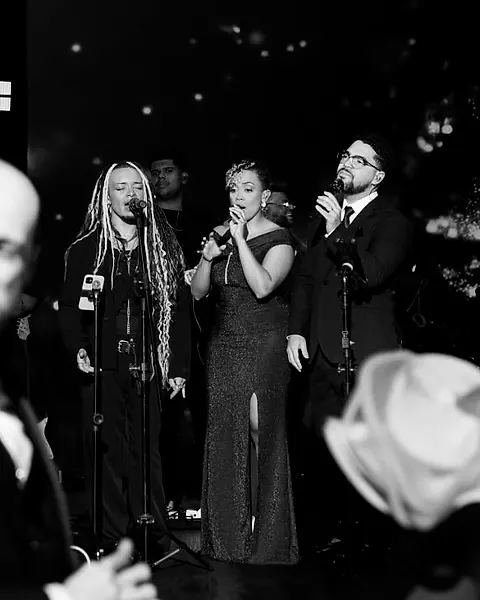 As vozes da Black SP cantando pros noivos, que assistem de frente pro palco