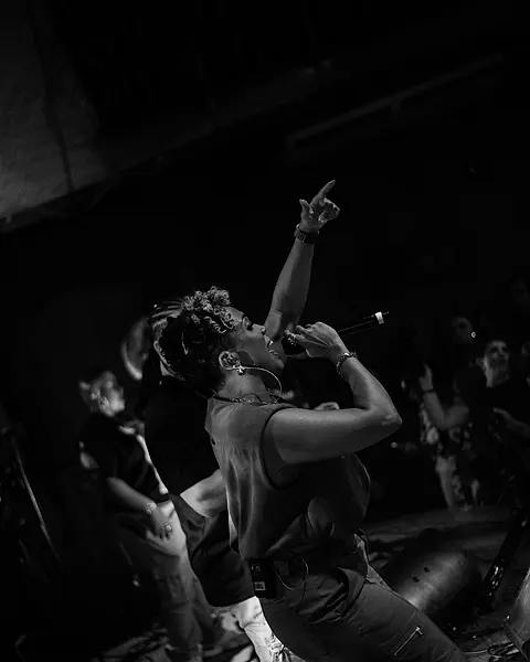 Cantora da Black SP apontando pro alto com a plateia atrás