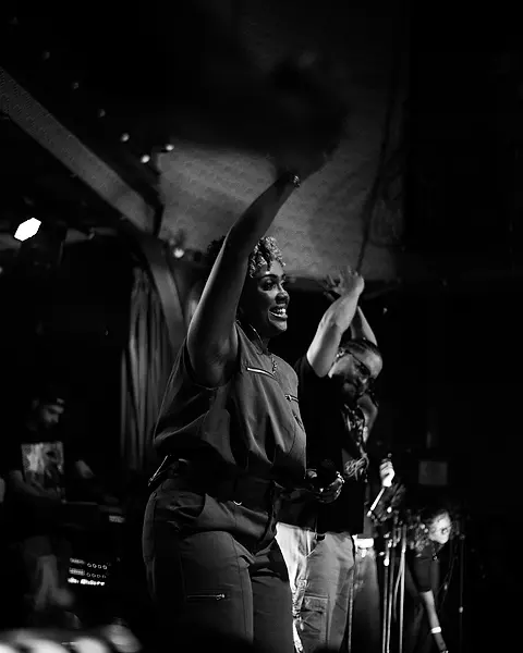 Cantora da Black SP de braço erguido, puxando a plateia